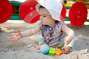 Adorable 9 months old baby playing outdoors - lifestyle portrait of mixed ethnicity Asian Caucasian baby girl playing with block