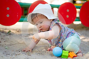 Adorable 9 months old baby playing outdoors - lifestyle portrait of mixed ethnicity Asian Caucasian baby girl playing with block