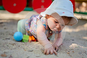 Adorable 9 months old baby playing outdoors - lifestyle portrait of mixed ethnicity Asian Caucasian baby girl playing with block