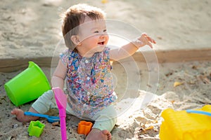 Adorable 9 months old baby playing outdoors - lifestyle portrait of mixed ethnicity Asian Caucasian baby girl playing with block