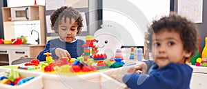 Adorable african american boys playing with construction blocks sitting on table at kindergarten