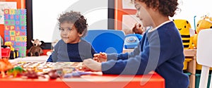 Adorable african american boys playing with maths puzzle game sitting on table at kindergarten