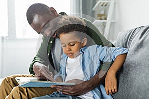 adorable african-american father and son reading