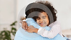 Adorable African American girl hugging her grandpa at home