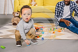 adorable african american toddler looking at camera while playing with father