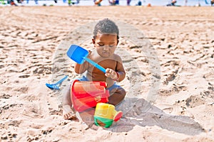 Adorable african american toddler playing with toys sitting on the sand at the beach