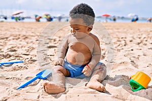 Adorable african american toddler playing with toys sitting on the sand at the beach