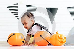 Adorable African baby kid dressing up in vampire fancy Halloween costume with black bat wings, cheerful little cute child go to