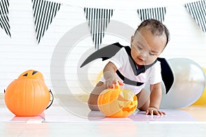 Adorable African baby kid dressing up in vampire fancy Halloween costume with black bat wings, cheerful little cute child go to