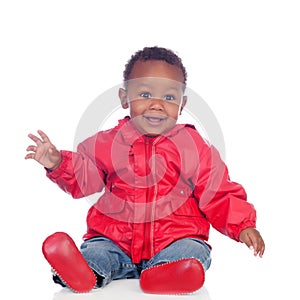 Adorable african baby sitting on the floor with red raincoat