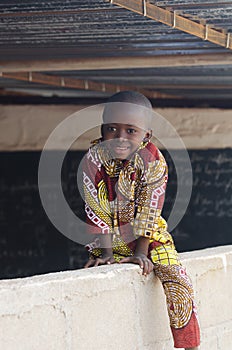 Adorable African Child Sitting on Wall at School