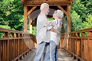 Adorable aged couple dancing while being on the bridge