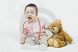 Adorable asian baby boy in pink shirt plays in doctor toy bear and red stethoscope.Health care and medical concept.