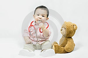 Adorable asian baby boy in pink shirt plays in doctor toy bear and red stethoscope.Health care and medical concept