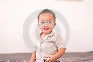 Adorable asian baby boy sitting in bedroom,Happy and laughing new born kid