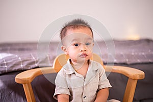 Adorable asian baby boy sitting on chair in bedroom,Happy new born kid looking to camera