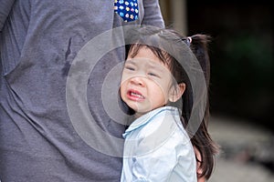 Adorable Asian girl is crying with tears on her cheeks. Child rested on her mother`s belly. Children is in pain from heartache.