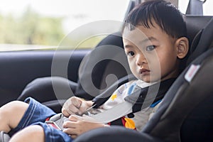 Adorable Asian kid boy Toddler age 1-year-old Protection Sitting in the Car Seat with Safety Belt Locked