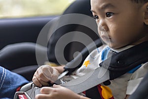 Adorable Asian kid boy Toddler age 1-year-old Protection Sitting in the Car Seat with Safety Belt Locked