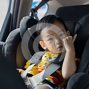 Adorable Asian kid boy Toddler age 1-year-old Protection Sitting in the Car Seat with Safety Belt Locked