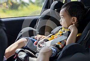 Adorable Asian kid boy Toddler age 1-year-old Protection Sitting in the Car Seat with Safety Belt Locked