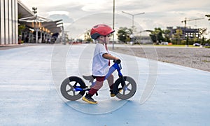 Adorable Asian kid boy Toddler age 1-year-old, Wearing a Safety Helmet and Learning to Ride a Balance Bike in the Play Space