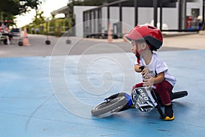 Adorable Asian kid boy Toddler age 1-year-old, Wearing a Safety Helmet and Learning to Ride a Balance Bike in the Play Space