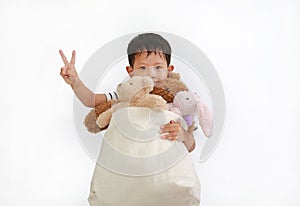 Adorable Asian little baby boy holding toys bag for donation on white background. Concept of Pass happiness to others and sharing