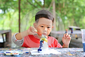 Adorable asian little baby boy painting on stucco doll