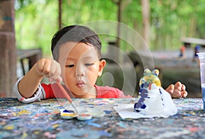 Adorable asian little baby boy painting on stucco doll