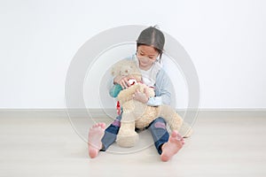 Adorable asian little child girl applying alcohol gel from plastic bottle for cleaning teddy bear hands for hygiene and anti virus