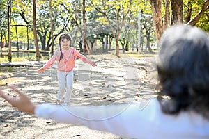 An adorable Asian little girl, granddaughter running to her grandmother in the park