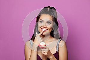 Adorable attractive nice charming amazed brunette young smiling woman fashion model holding cupcake on colorful pink background