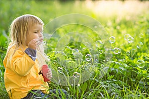 Adorable baby blow soap bubbles in park