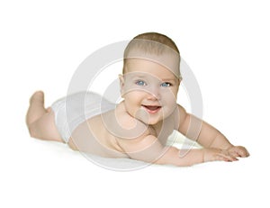 Adorable baby boy with blue eyes laughing and lying on stomach on bedding wearing diaper isolated on white background