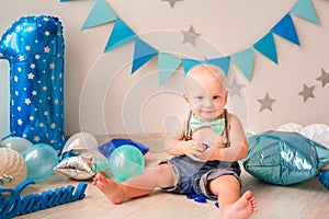 Adorable baby boy celebrating his first birthday. Smash cake