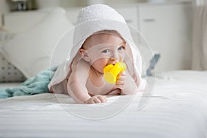 Adorable baby boy covered in towel holding yellow rubber duck in