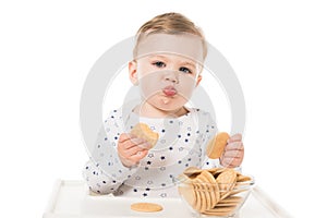 adorable baby boy eating cookies sitting in highchair