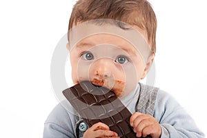 Adorable baby boy eating a plate of chocolate