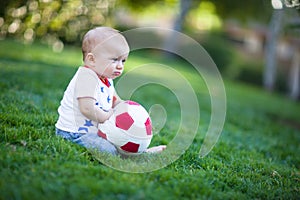 Adorable baby boy holding a red and white soccer ball