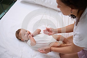 Adorable baby boy laughing and smiling looking at his mom cuddling him. Babyhood and infancy. Maternity and baby care