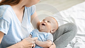 Adorable baby boy looking at mom, lying on her laps