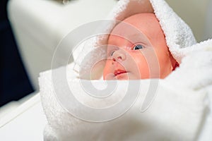 Adorable baby boy looking out under white towel