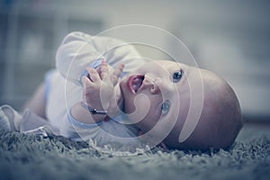 Adorable baby boy lying on carpet. Close up.