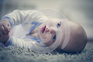 Adorable baby boy lying on carpet. Close up.