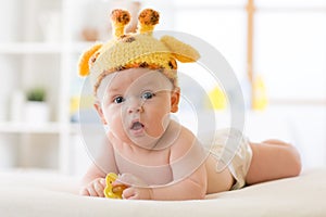 Adorable baby boy lying on tummy and weared funny giraffe hat