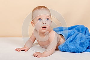 Adorable baby boy lying under the towel and having fun after bath