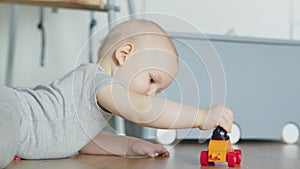 Adorable baby boy playing with car toy on the floor