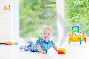 Adorable baby boy playing with colorful ball and toy car