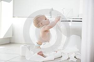 Adorable baby boy playing with toilet paper